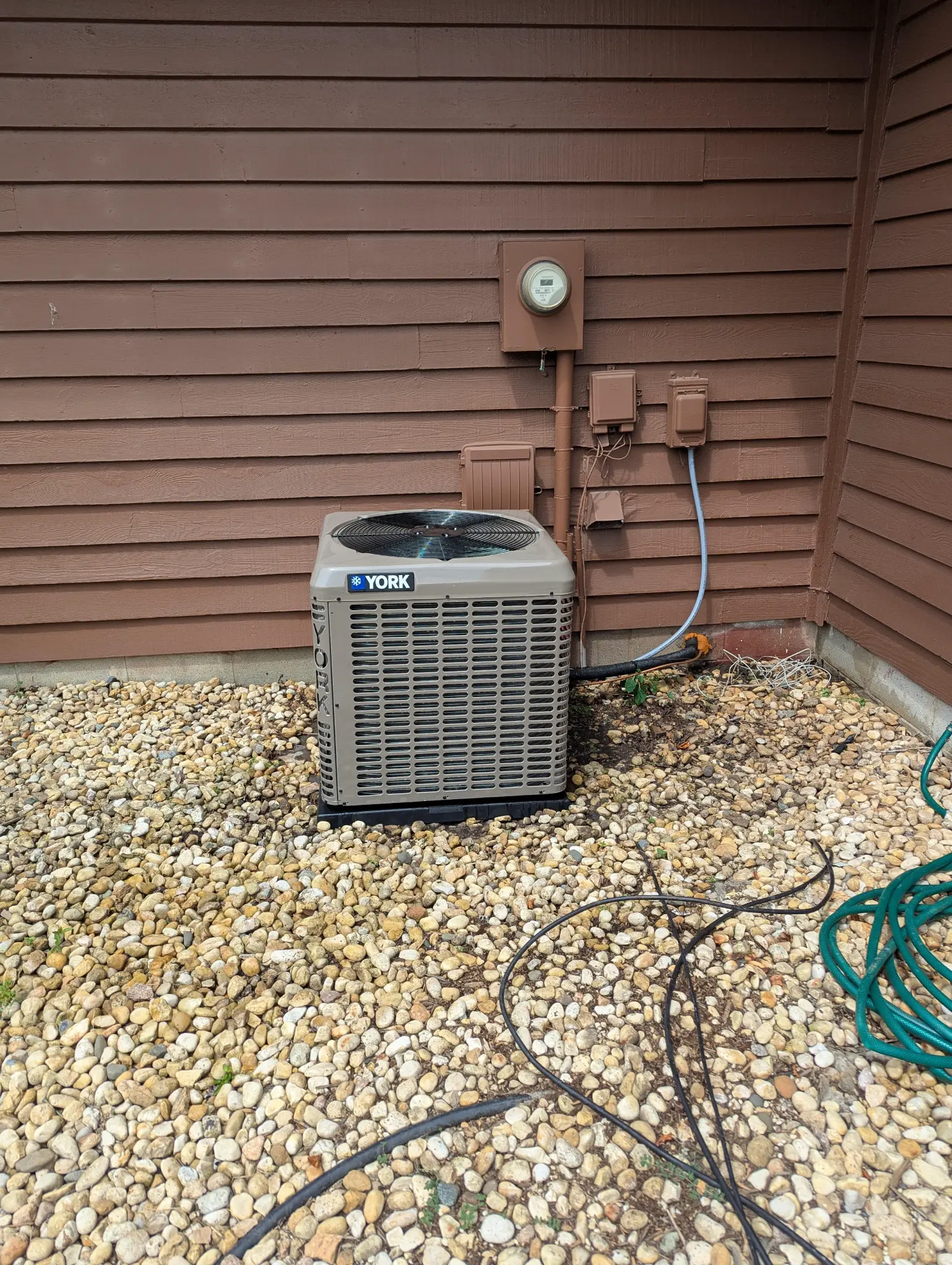 Outdoor air conditioning condenser beside residential siding